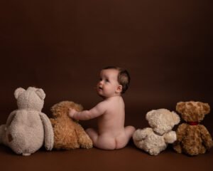 7 month baby sitting in photo studio with teddies