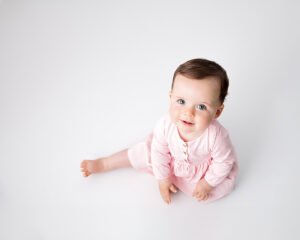 Baby girl in pink sitting up and smiling for the Bridgwater photographer