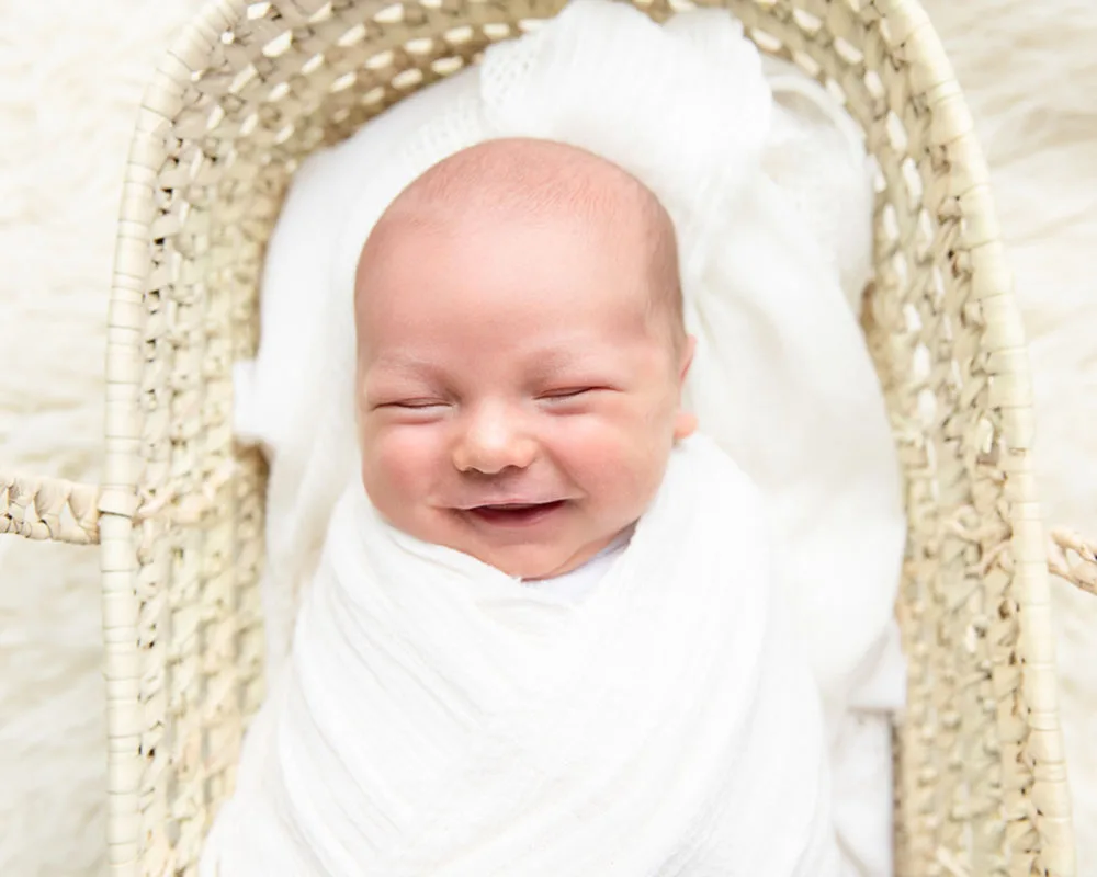 Baby smiling in Moses basket