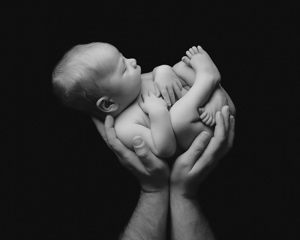 Newborn baby being raised up by daddy's hands