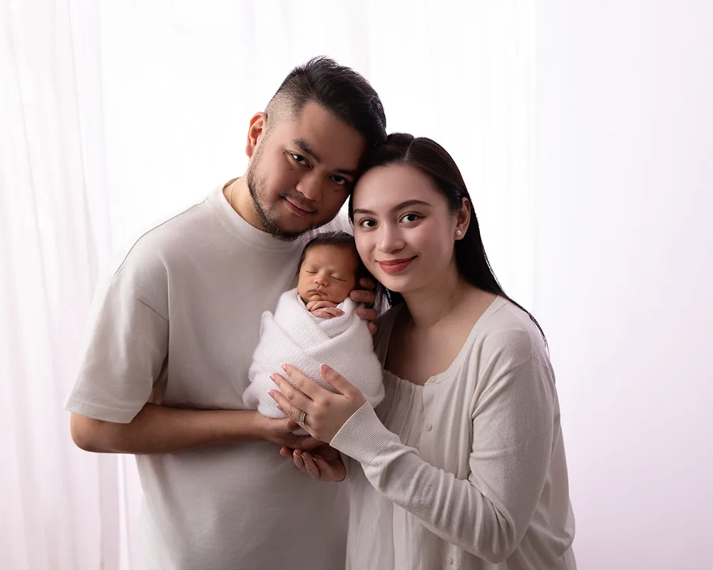 Sharon-Lewis-Photography-Taunton-photographer Mum and dad holding newborn baby all dressed in white