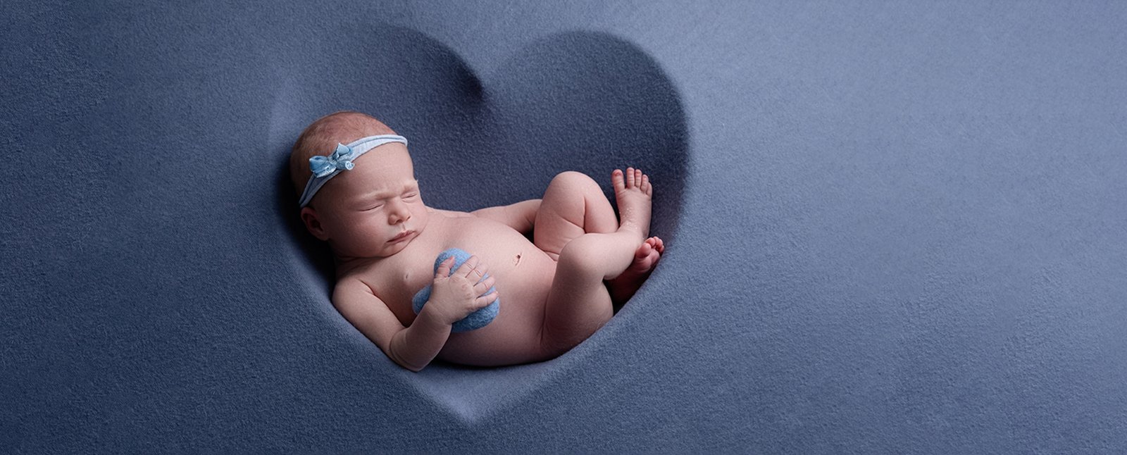 Baby girl sleeping in blue heart shaped with headband